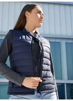 100% poliestere (riciclato). Gilet imbottito da donna in poliestere riciclato, finitura idrorepellente e antimacchia BIONIC-FINISH ECO, imbottitura antifreddo sorona®AURA, non trapuntato nella parte anteriore e posteriore per una facile stampa o ricamo, zip a tutta lunghezza, collo alto con bottone a pressione, 2 tasche laterali con zip, 1 tasca interna con zip, zip: YKK