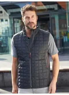 100% polyester. Doublure: 100% polyamide. Rembourrage: 100% polyester. Gilet polaire mélange, tissu easy-care doux. Matelassé au front, au dos et au col. Coutures plates contrastées aux épaules. 2 poches latérales zippées, 2 poches internes. 280 g/m2. Lavable à 30°C.