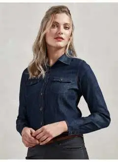 100% cotone ring spun denim. Camicia donna manica lunga con taschini sul petto, chiusura con bottoni sui polsini e orlo arrotondato sul fondo, leggermente sfiancata ai lati.