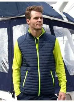 100% poliéster. Chaqueta sin mangas impermeable, anti-viento, transpirable, bolsillos laterales con cremallera, cierre frontal con cremallera y mentonera, cremalleras en contraste, cintura y sisas elastizadas, forro aislado REPREVE.